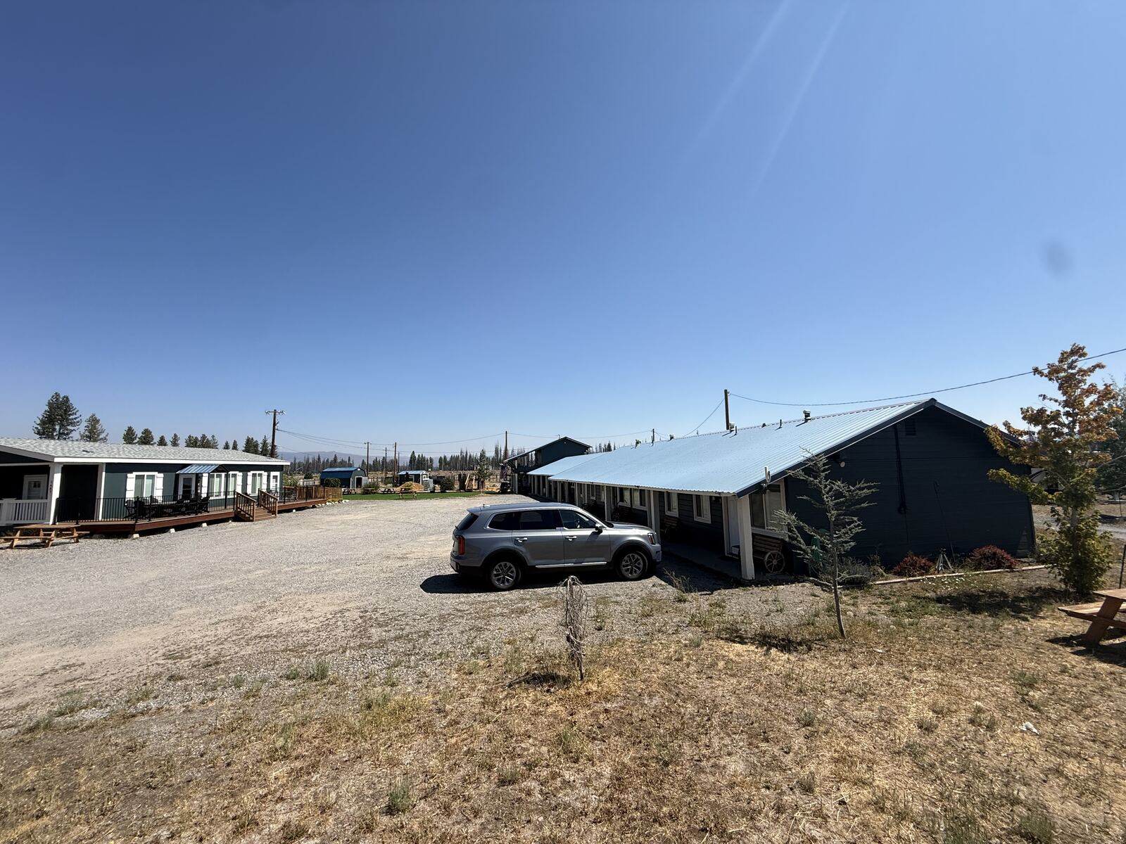 The gravel lot at Cedar Lodge with the house and its deck on the left and the motel under its metal roof on the right.